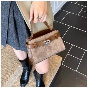 Detail of vintage brown textured handbag showing silver metal buckle and top handle