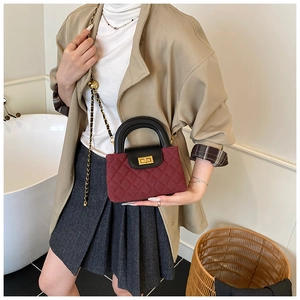Detail of burgundy quilted mini bag with gold-tone twist lock and woven chain strap