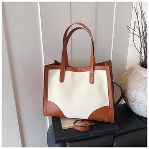 Détail du sac cabas en toile bicolore avec anses en cuir marron et bandoulière réglable