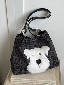 Leopard print tote bag with plush dog patch and slim black shoulder straps on book display