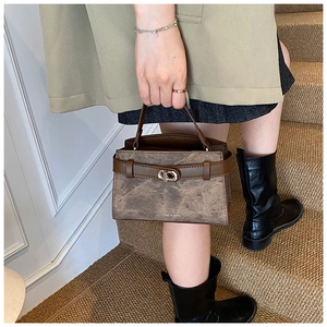 Detailed view of a vintage brown leather bucket bag with metallic buckle and textured finish