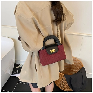 Detail of the chic burgundy quilted leather handbag with gold metal lock and chain strap