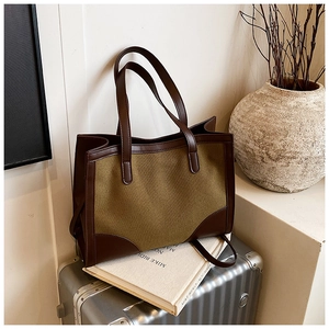 Détail du tissu olive contrastant et des lanières en cuir marron sur le grand sac cabas