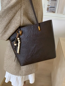 Large dark brown leather tote bag with unique wood bead charm and long shoulder straps