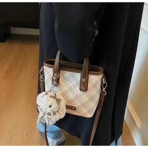 Close-up of vintage check crossbody bag with leather trim and plush rabbit charm detail