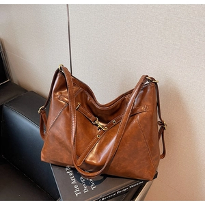 Close-up of caramel brown tote bag with premium faux leather texture and metal buckle detail