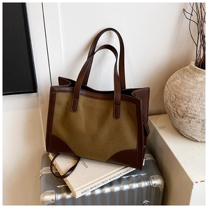 Détail du grand sac cabas en toile olive avec anses en cuir brun sur une valise