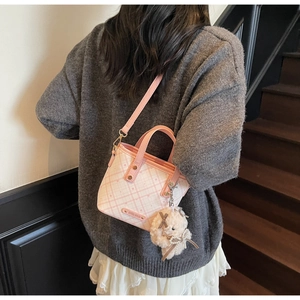 Lifestyle view of a pink plaid bucket bag with a cute bear charm on a model's shoulder