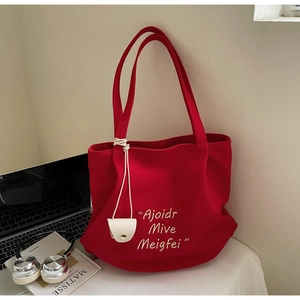 Detail of red canvas tote bag with embroidery, small pouch and artistic lifestyle props