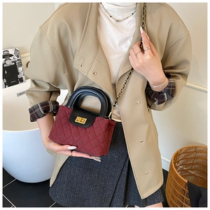 Detail of red quilted fabric bag with golden twist lock and black leather handle