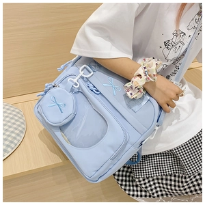 Close-up of light blue ita bag with bow embroidery and transparent PVC window on a model