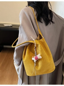 Large yellow suede tote bag with puppy charm accessory shown on model in home setting
