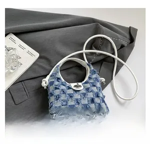 Macro view of blue checkered denim bucket bag with frayed edges and metal twist lock