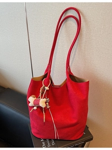 Large red suede tote bag with dog charm displayed on a book in a modern interior