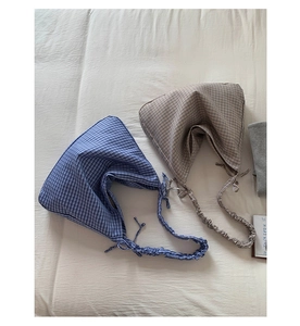 Detail view of vintage plaid shoulder bags in blue and beige with pleated cotton texture