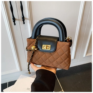 Detail of quilted brown suede handbag with black flap and gold twist lock closure