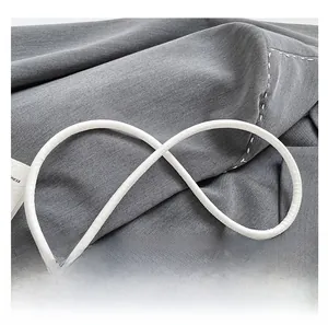 Detail showing white cylindrical leather strap and textured grey denim fabric of bucket bag