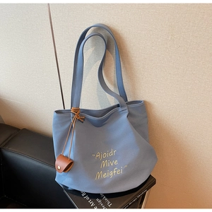 Close-up of blue canvas tote bag featuring yellow cursive text and a brown leather charm