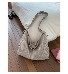 Detailed view of the plaid hobo bag with pleated shoulder strap and bow ribbon accent