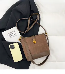 Brown bucket bag featuring vintage gold hardware and contrast textures on white surface