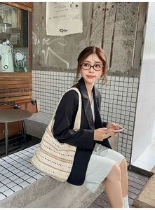 Model wearing a bohemian hollow crochet bucket bag with brown stripes in a cafe