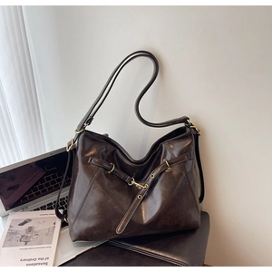 Detail of dark brown faux leather tote featuring metallic buckle and polished texture
