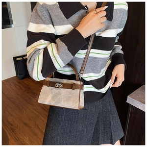 Detail view of a beige and brown trapezoid crossbody bag with metallic turn-lock closure