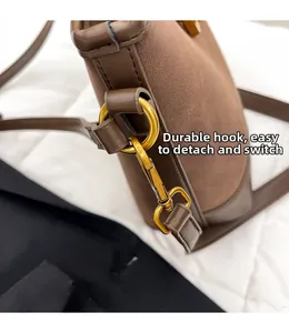 Detail of durable gold metal lobster clasp on brown suede shoulder bag strap