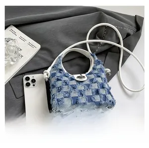 Detail of blue and white checkered denim bucket bag featuring frayed edges and silver twist lock