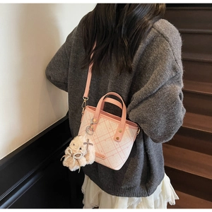 Pink and white checkered bucket bag featuring a plush bunny charm and crossbody strap