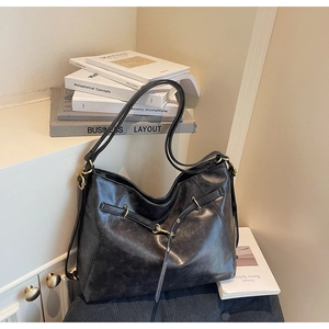 Detail shot of the black textured leather tote bag with elegant golden metal buckle