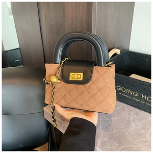 Detail of brown quilted suede mini bag with black leather flap and gold chain ball