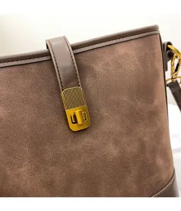 Detail of vintage gold metal clasp and premium brown suede stitching on bucket bag