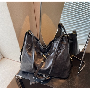 Detail of grey textured tote bag with vintage metal buckles and adjustable dual straps