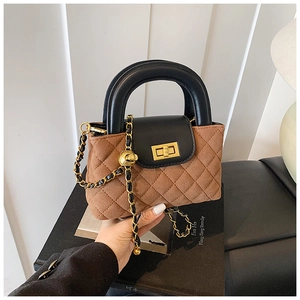 Close-up of brown suede quilted handbag with black leather flap and gold chain strap