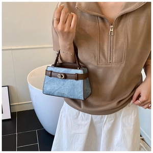 Detail of light blue stone-textured bucket bag with brown leather handle and metal buckle