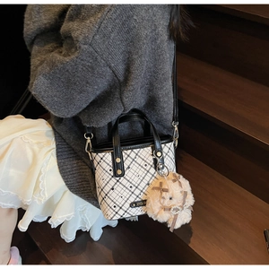 Black and white checkered bucket bag with a cute plush charm accessory shown on model