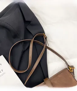 Detail of adjustable leather strap and vintage gold buckle on a brown suede bucket bag