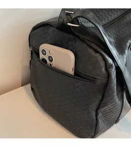 Dettaglio della tasca laterale con zip su una borsa da viaggio nera in pelle intrecciata