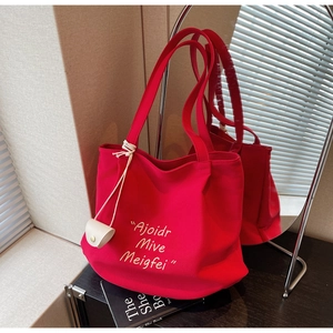 Detail of red canvas tote bag with yellow embroidery and a small PU coin purse charm