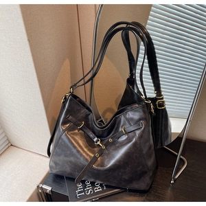Detail of vintage black leather tote bag with metallic ring and buckle on strap