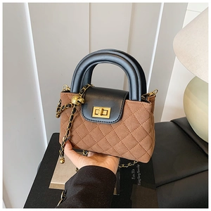 Detail of quilted brown suede bag with black handle and gold twist lock in French retro style