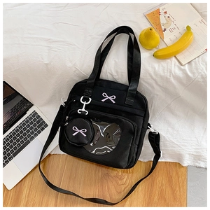 Detail of black canvas tote bag with heart-shaped window and pink bow embroidery