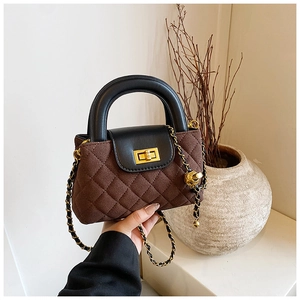 Detail of the quilted texture and golden twist lock on the brown and black chain bag