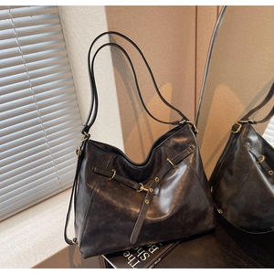 Detail of vintage dark gray leather tote featuring gold metal eyelets and decorative drawstring