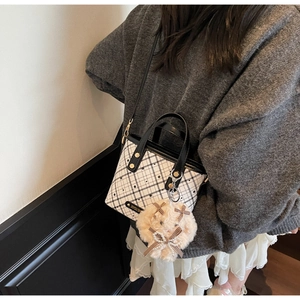 Detail of checkered bucket bag with contrast handle and cute teddy bear charm