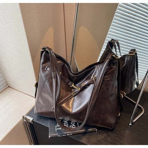Close-up of a dark brown large tote bag with oil wax leather texture and eyelet strap details