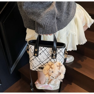 Detail of black and white checkered bucket bag with a cute plush dog charm on a strap
