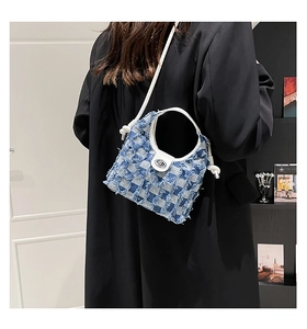 Detail of denim bucket bag showing distressed blue plaid texture and silver metal twist lock