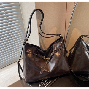 Macro detail of dark brown polished leather texture and golden buckle on tote bag